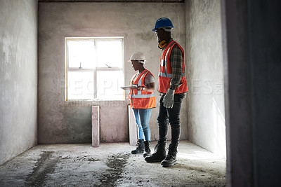 Buy stock photo Shot of a young man and woman using a digital tablet while working at a construction site