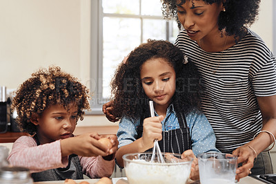 Buy stock photo Shot of two children baking at home with the help of their mother