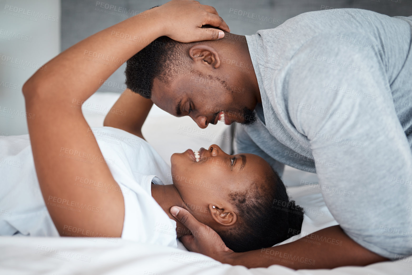 Buy stock photo Shot of an affectionate young couple relaxing on their bed together at home