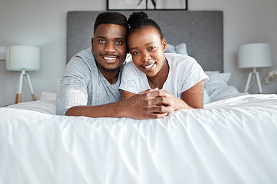 Buy stock photo Portrait of an affectionate young couple relaxing on their bed together at home