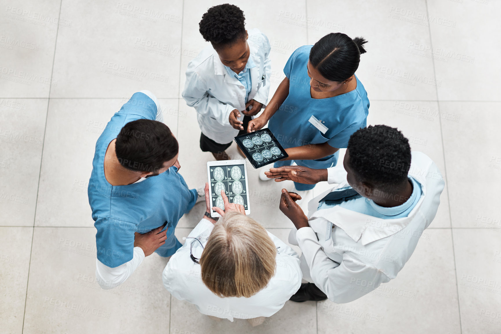 Buy stock photo High angle shot of a group of medical practitioners analysing brain scans on a digital tablet in a hospital