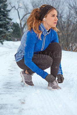 Buy stock photo Shot of a woman tying her laces while out for a run on a winter's day