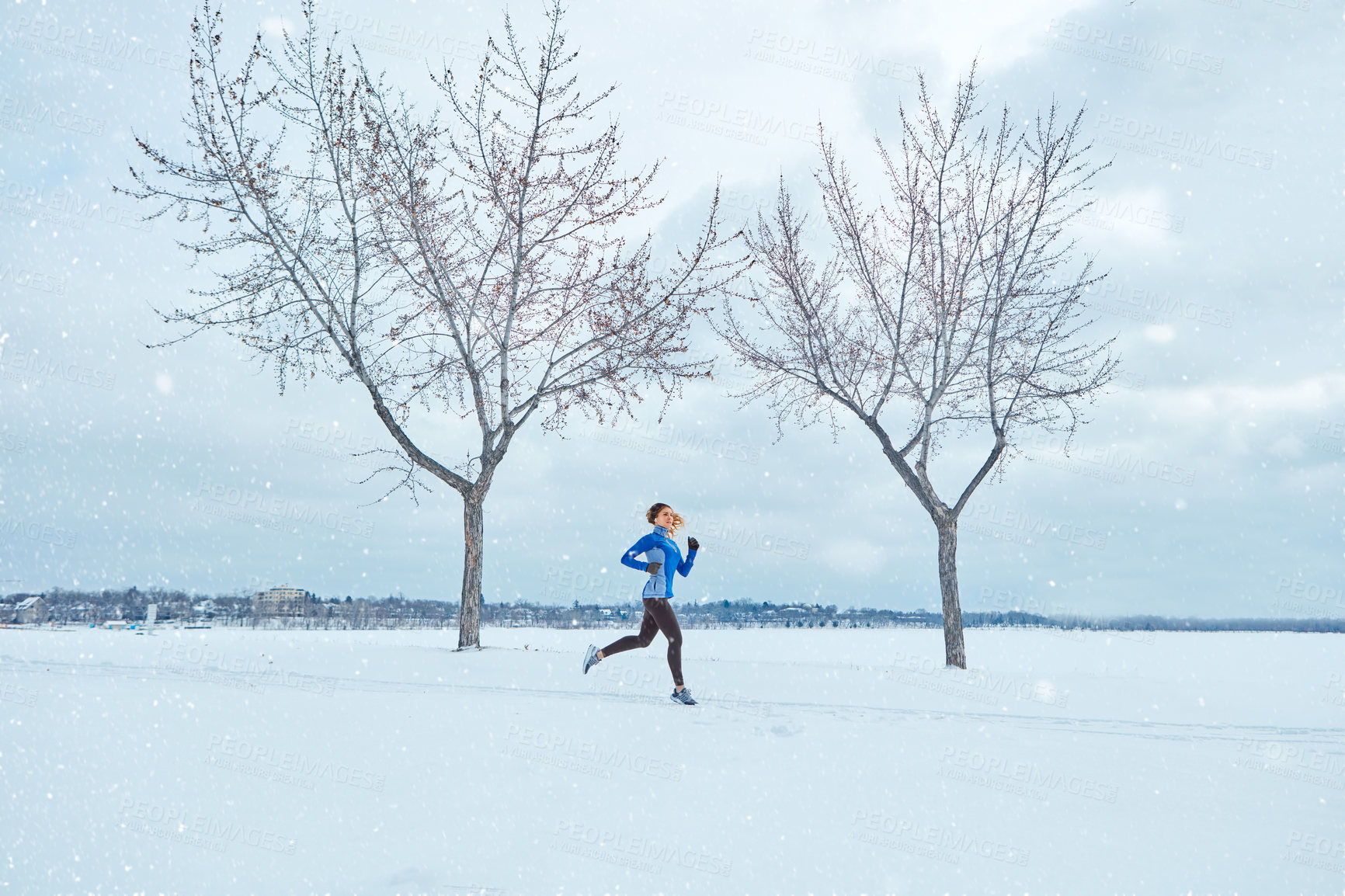 Buy stock photo Shot of a woman wearing warm clothing while out for a run through the snow