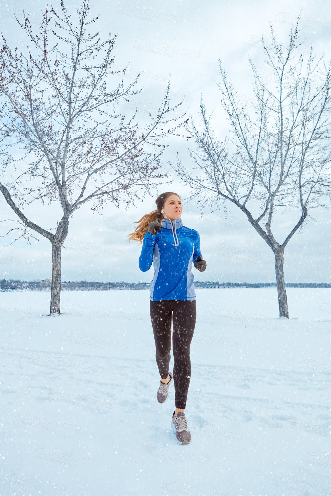 Buy stock photo Shot of a woman wearing warm clothing while out for a run through the snow