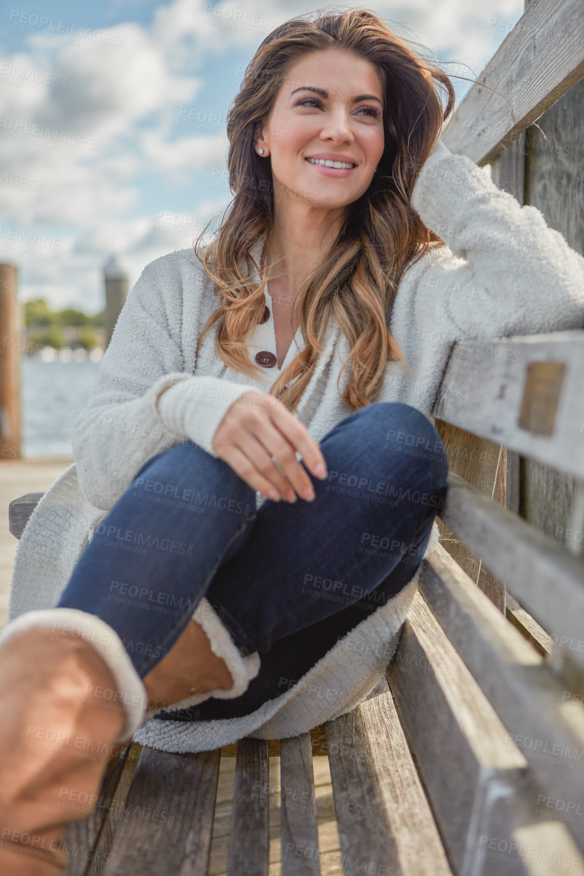 Buy stock photo Shot of a beautiful young woman relaxing on a bench outdoors