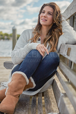 Buy stock photo Shot of a beautiful young woman relaxing on a bench outdoors