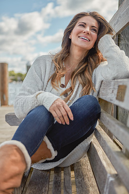 Buy stock photo Shot of a beautiful young woman relaxing on a bench outdoors