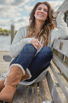 Buy stock photo Shot of a beautiful young woman relaxing on a bench outdoors