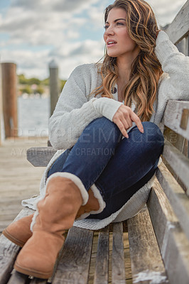 Buy stock photo Shot of a beautiful young woman relaxing on a bench at a lake