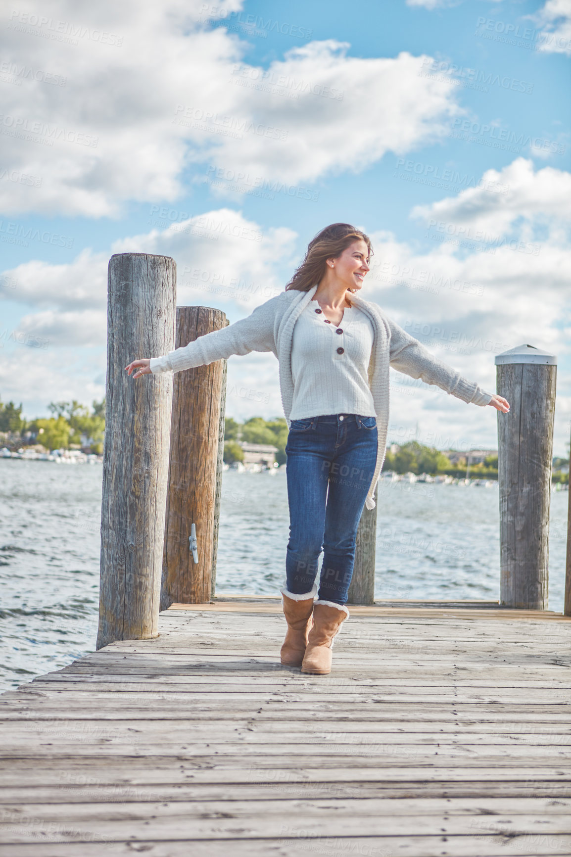 Buy stock photo Shot of a beautiful young woman walking along a pier at a lake