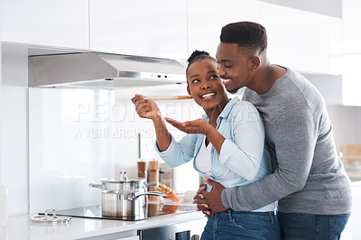 Buy stock photo Shot of a man embracing his wife from behind while she's busy cooking