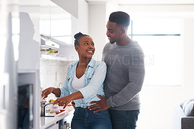 Buy stock photo Shot of a man embracing his wife from behind while she's busy cooking