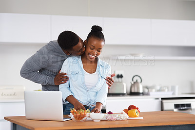 Buy stock photo Shot of a man embracing his wife from behind while she's with chopping vegetables