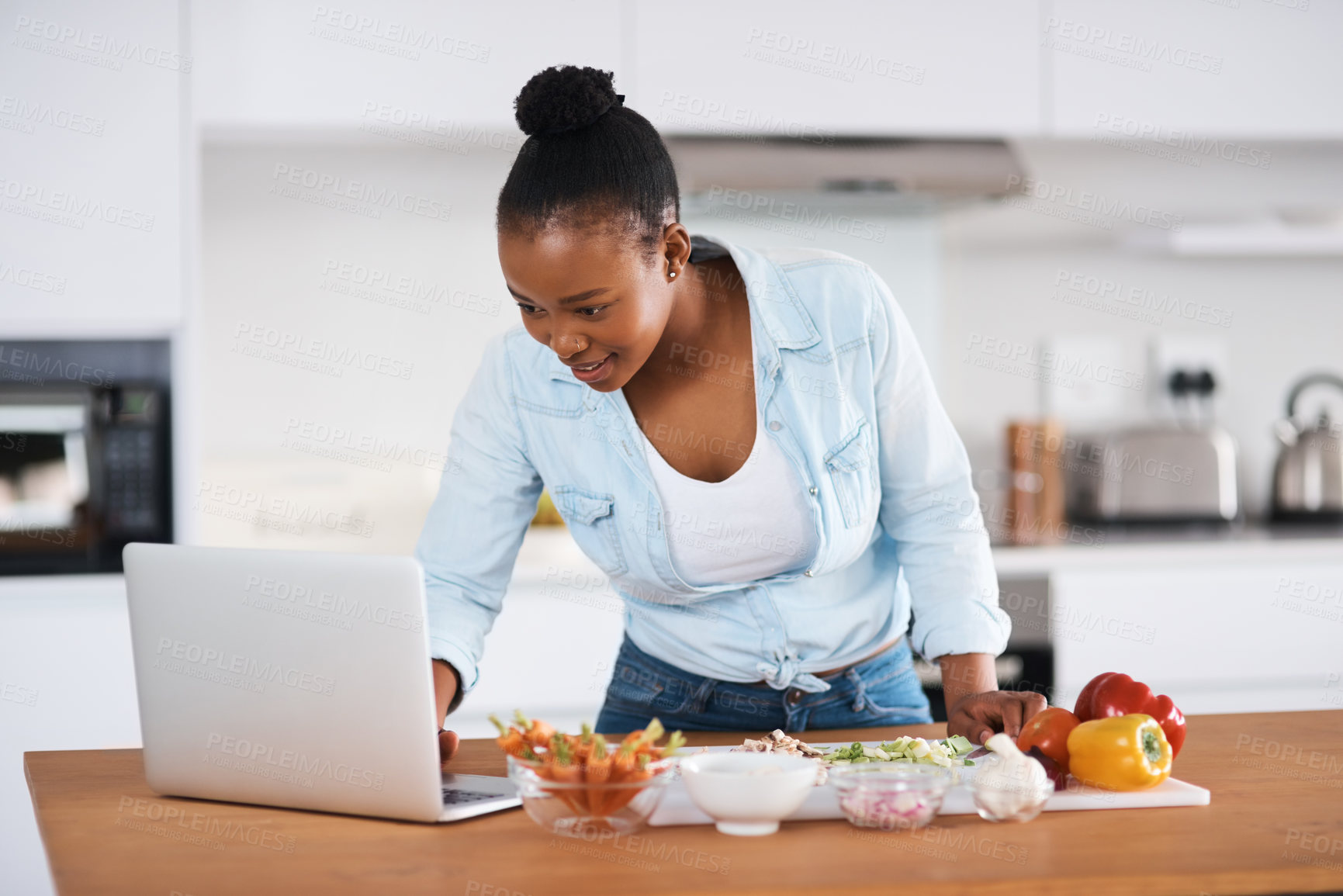 Buy stock photo Black woman, laptop and cooking meal in kitchen, search online recipe and vegetables for nutrition. Female person, ingredients and food in home, vegan cuisine and meal prep or reading instructions