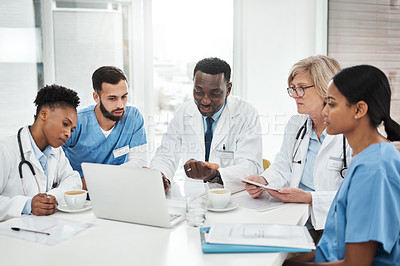 Buy stock photo Shot of a group of medical practitioners using a laptop during a meeting in a hospital boardroom