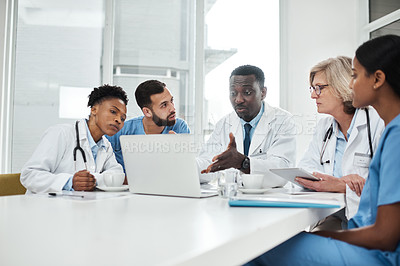 Buy stock photo Shot of a group of medical practitioners using a laptop during a meeting in a hospital boardroom