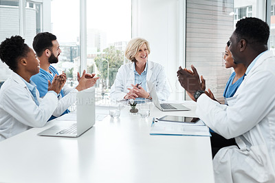 Buy stock photo Shot of a group of medical practitioners applauding a colleague during a meeting in a hospital boardroom