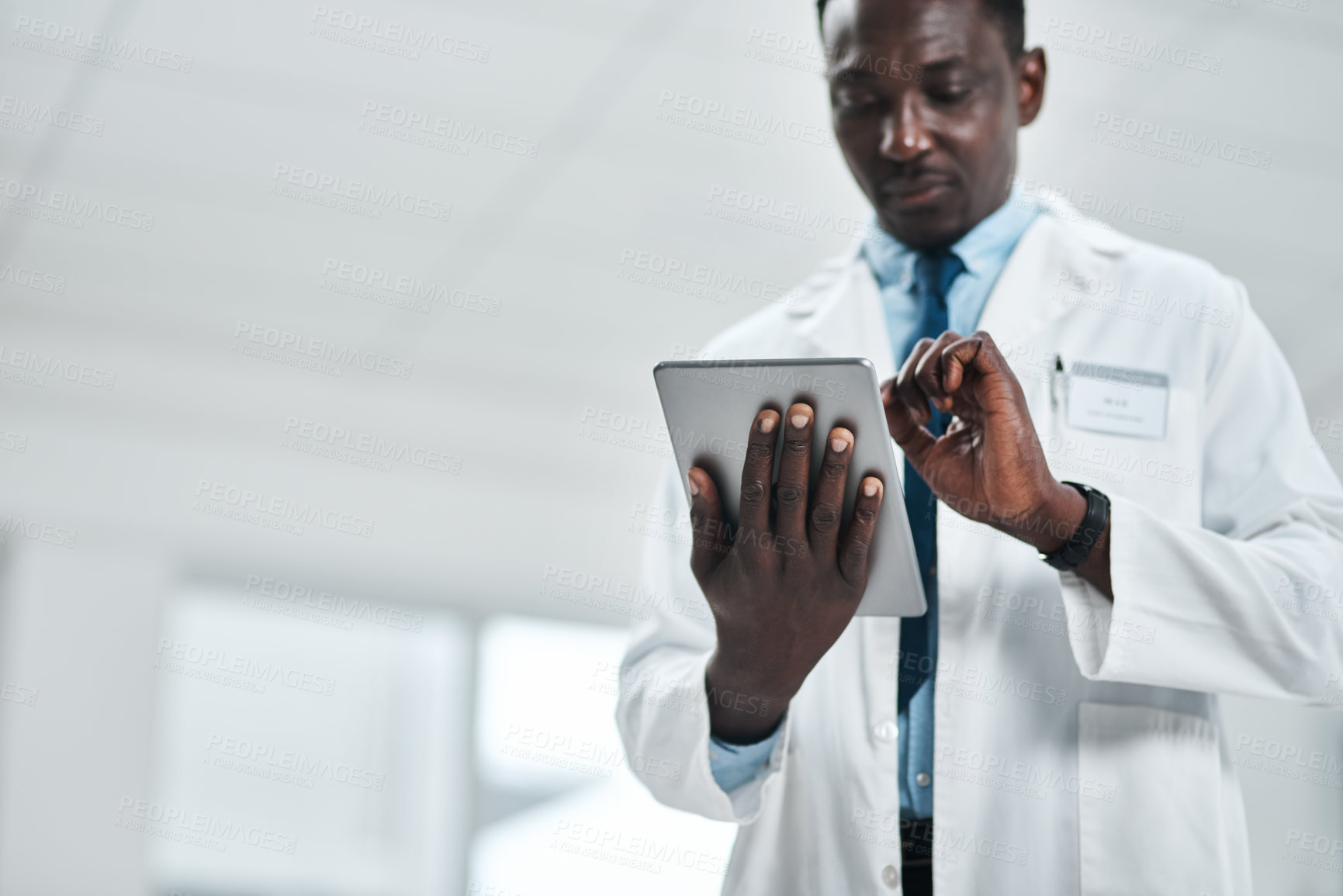 Buy stock photo Shot of a mature doctor using a digital tablet in a hospital