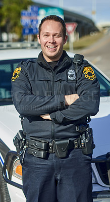 Buy stock photo Cropped portrait of a handsome young policeman standing with his arms crossed while out on patrol