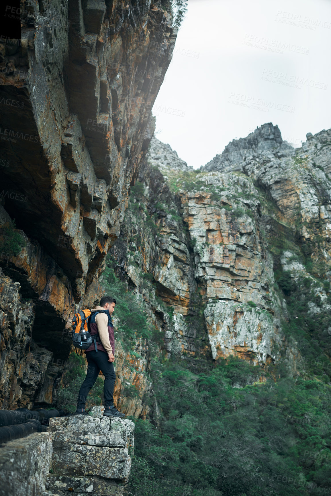 Buy stock photo Shot of a young man standing on a cliff while out on a hike