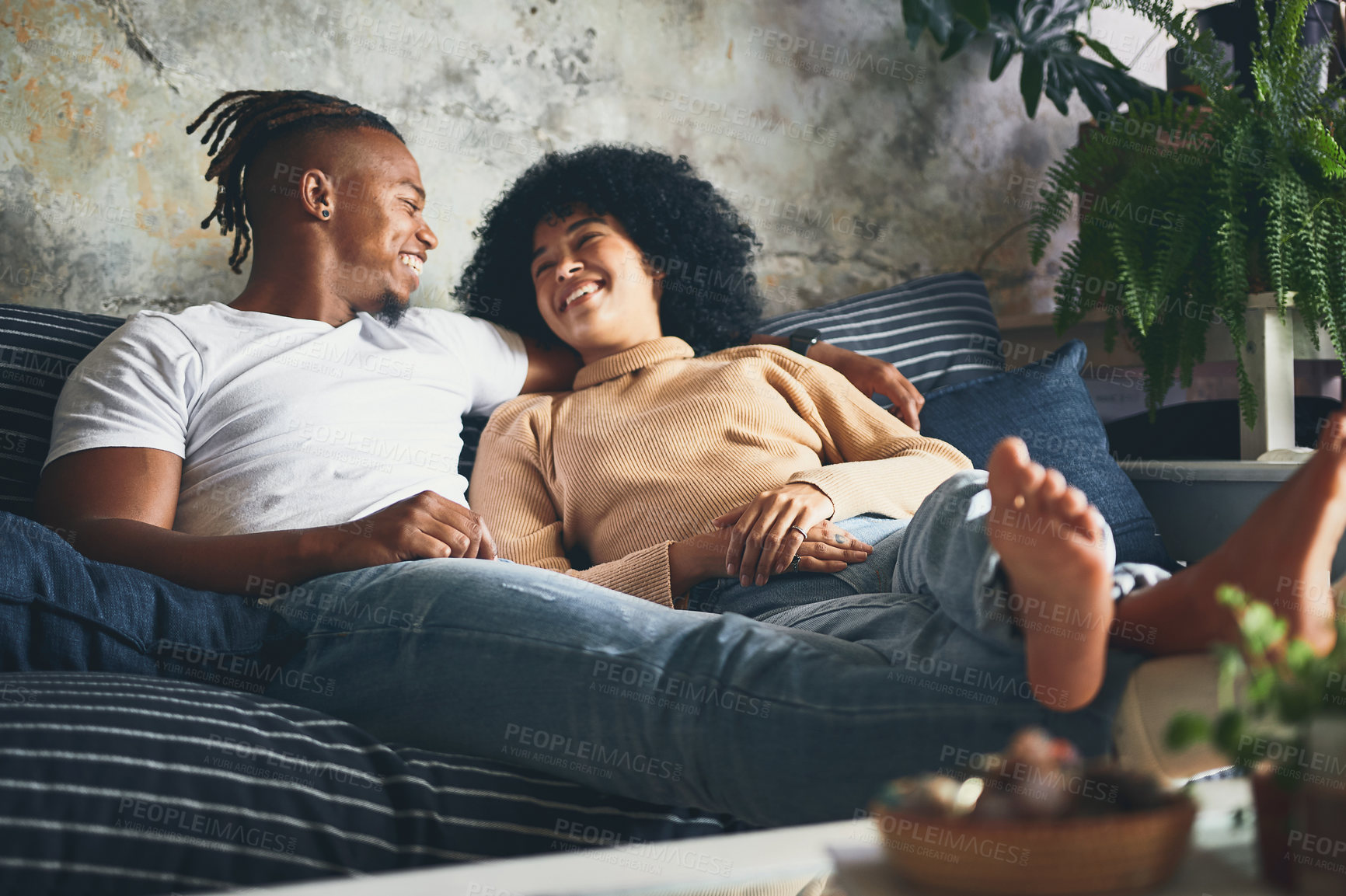 Buy stock photo Shot of a young couple relaxing together on a sofa at home