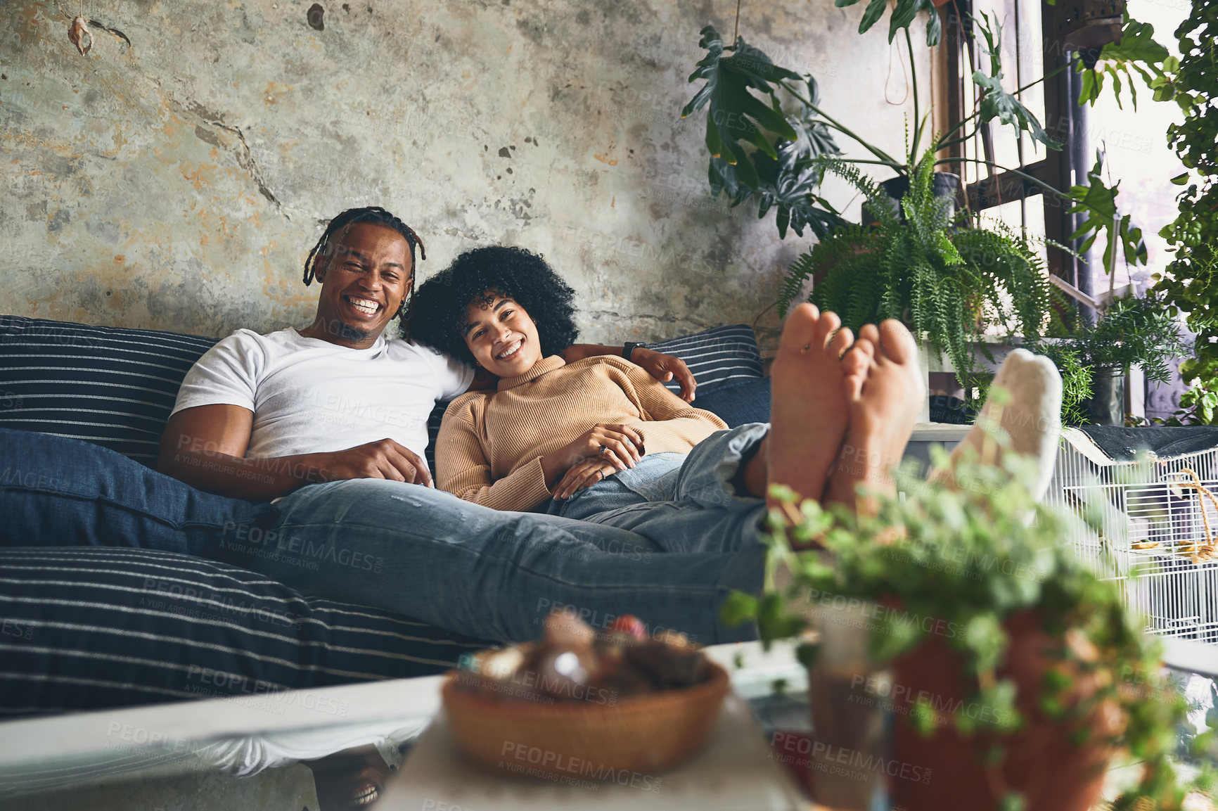 Buy stock photo Portrait of a young couple relaxing together on a sofa at home