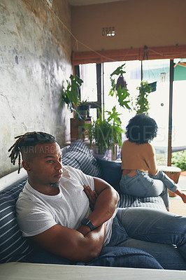 Buy stock photo Shot of a young man looking upset after an argument with his partner at home