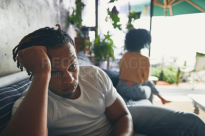 Buy stock photo Shot of a young man looking upset after an argument with his partner at home