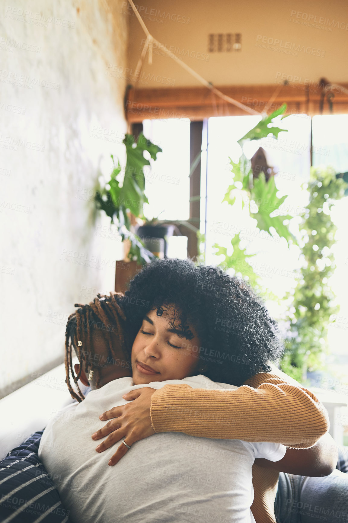 Buy stock photo Shot of a young woman hugging her boyfriend at home