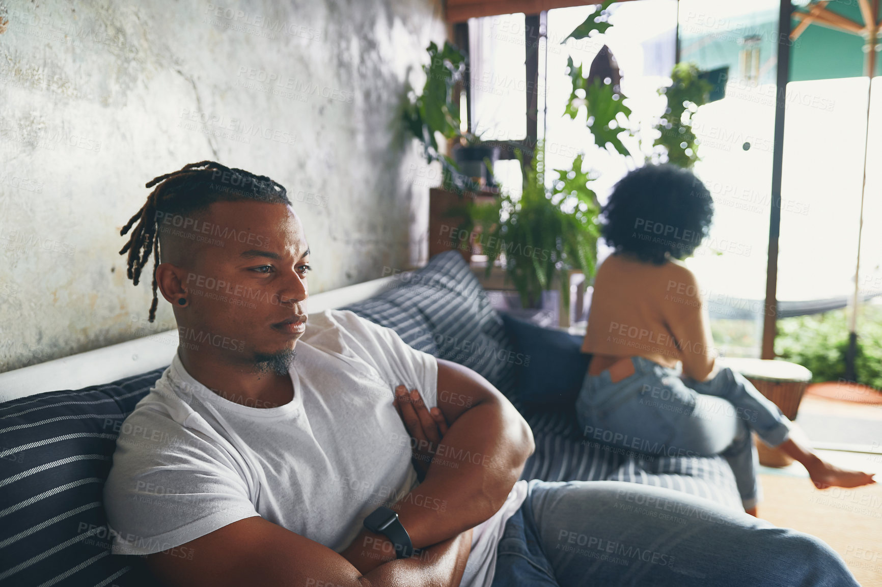 Buy stock photo Shot of a young man looking upset after an argument with his partner at home