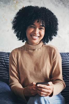 Buy stock photo Portrait of a young woman using a cellphone while relaxing on a sofa at home