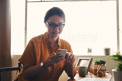 Buy stock photo Shot of a young woman using a smartphone while working from home