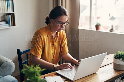 Buy stock photo Shot of a young woman using a laptop while working from home
