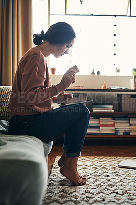 Buy stock photo Shot of a young woman using a digital tablet and credit card at home