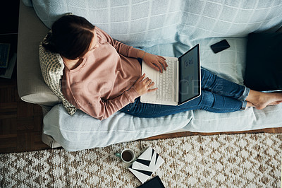 Buy stock photo High angle shot of a young woman using a laptop on the sofa at home