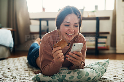 Buy stock photo Shot of a young woman using a smartphone and credit card at home