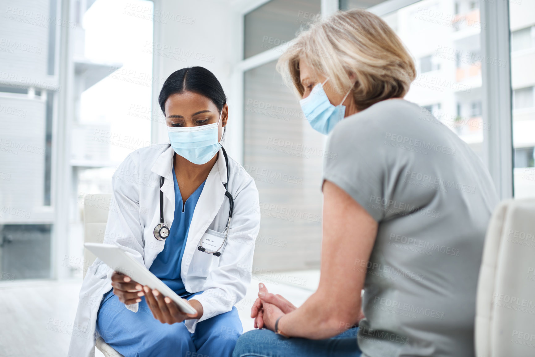 Buy stock photo Shot of a young doctor using a digital tablet during a consultation with a senior woman