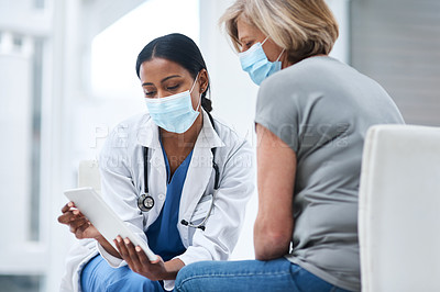 Buy stock photo Shot of a young doctor using a digital tablet during a consultation with a senior woman
