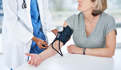 Buy stock photo Shot of a doctor examining a senior woman with a blood pressure gauge