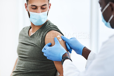 Buy stock photo Shot of a doctor applying a band aid after injecting a patient in his arm during a consultation at a clinic