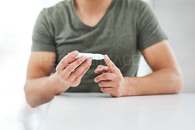 Buy stock photo Shot of an unrecognisable man using a blood sugar test on his finger