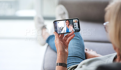 Buy stock photo Shot of a senior woman using a smartphone to make a video call with her doctor on the sofa a home