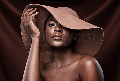 Buy stock photo Shot of a beautiful young woman wearing a hat while posing against a brown background