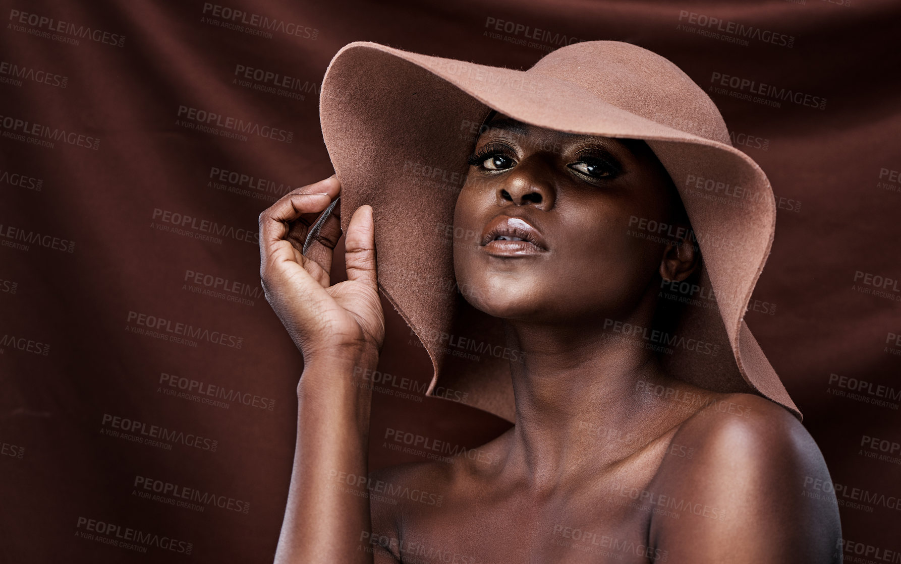 Buy stock photo Shot of a beautiful young woman wearing a hat while posing against a brown background