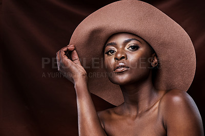 Buy stock photo Shot of a beautiful young woman wearing a hat while posing against a brown background