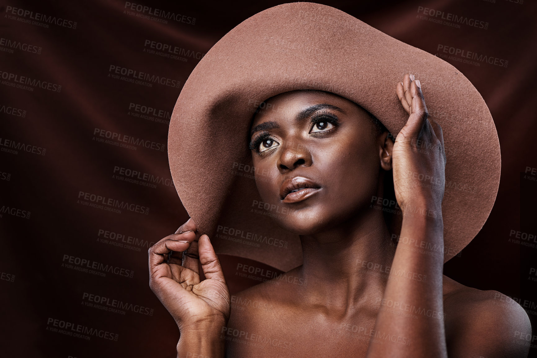 Buy stock photo Shot of a beautiful young woman wearing a hat while posing against a brown background