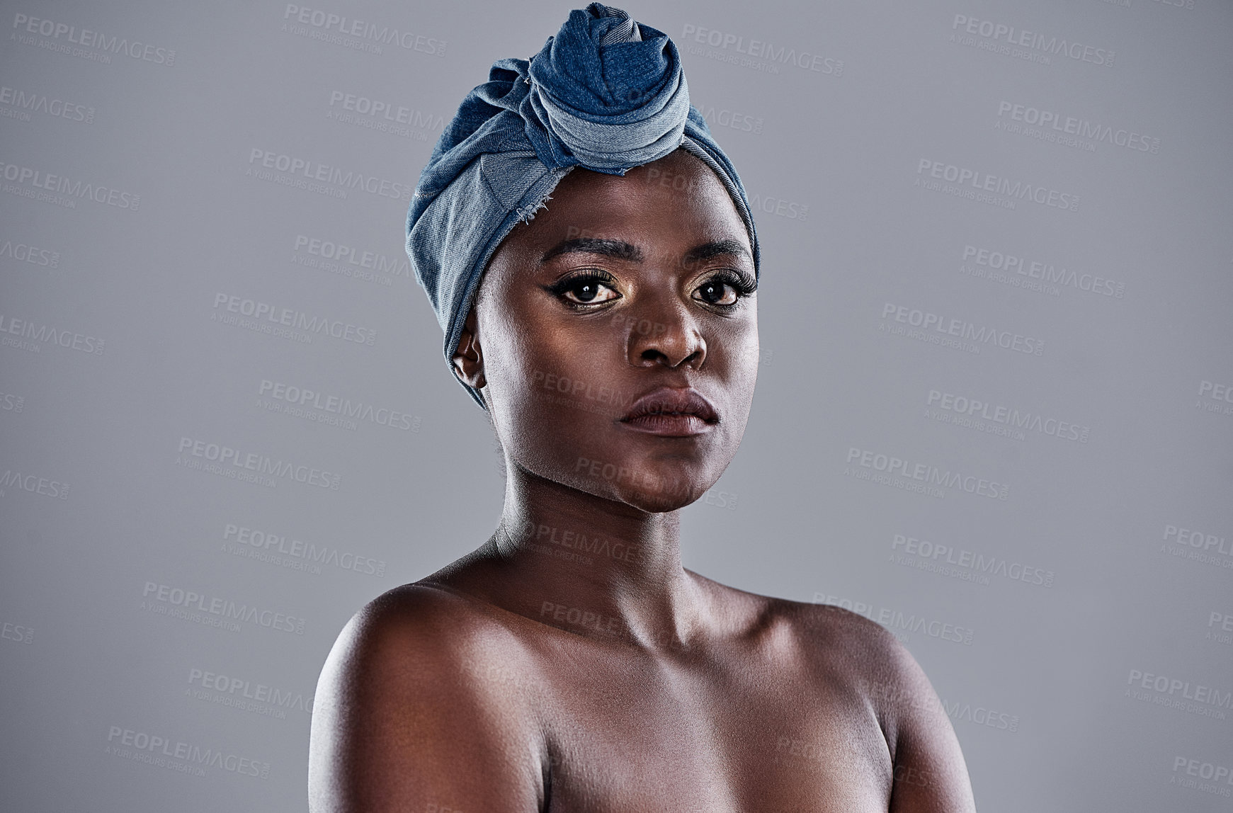 Buy stock photo Shot of a beautiful young woman wearing a denim head wrap while posing against a grey background