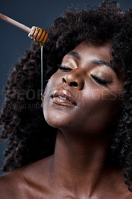 Buy stock photo Shot of a beautiful young woman holding a honey dipper against her face