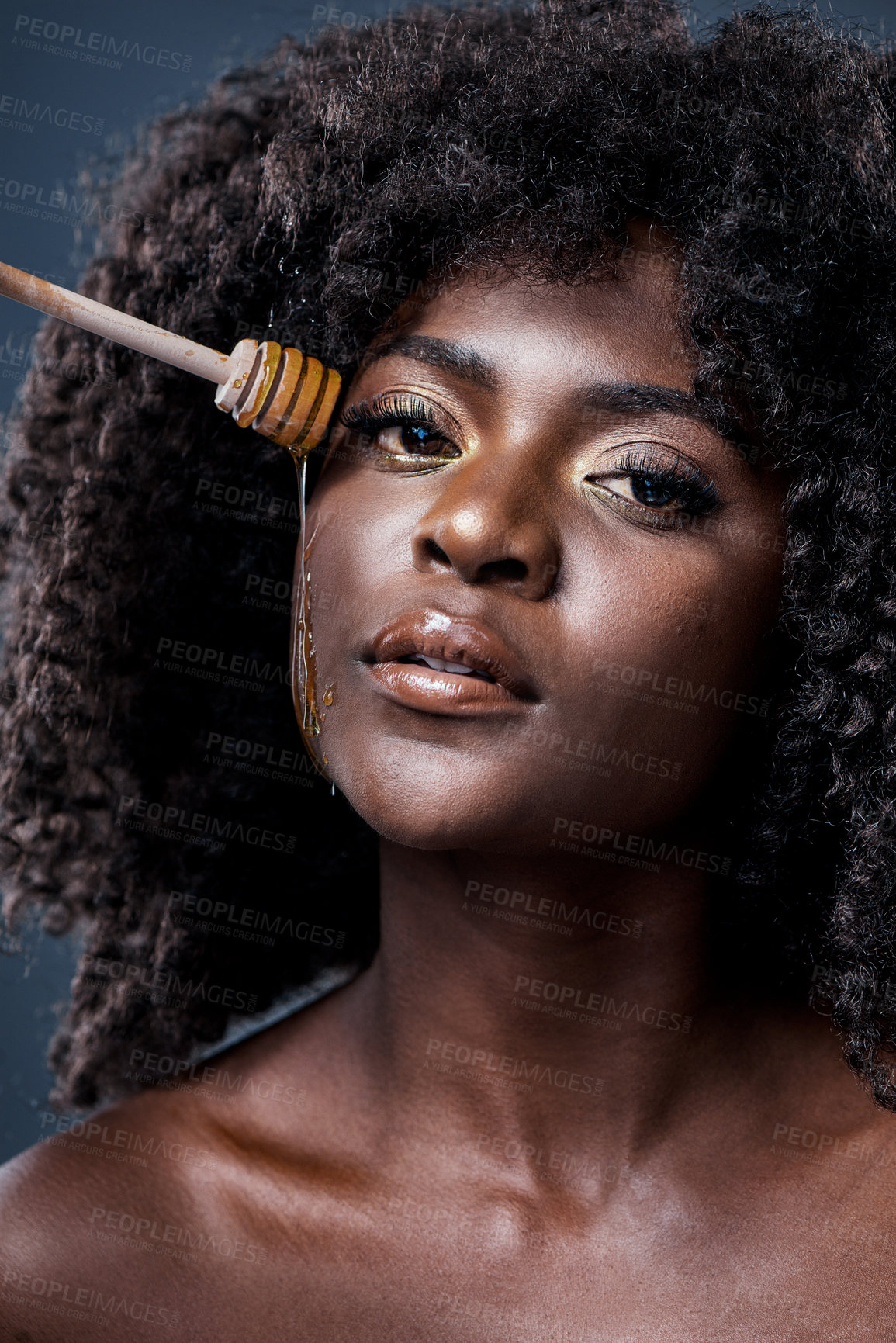 Buy stock photo Shot of a beautiful young woman holding a honey dipper against her face