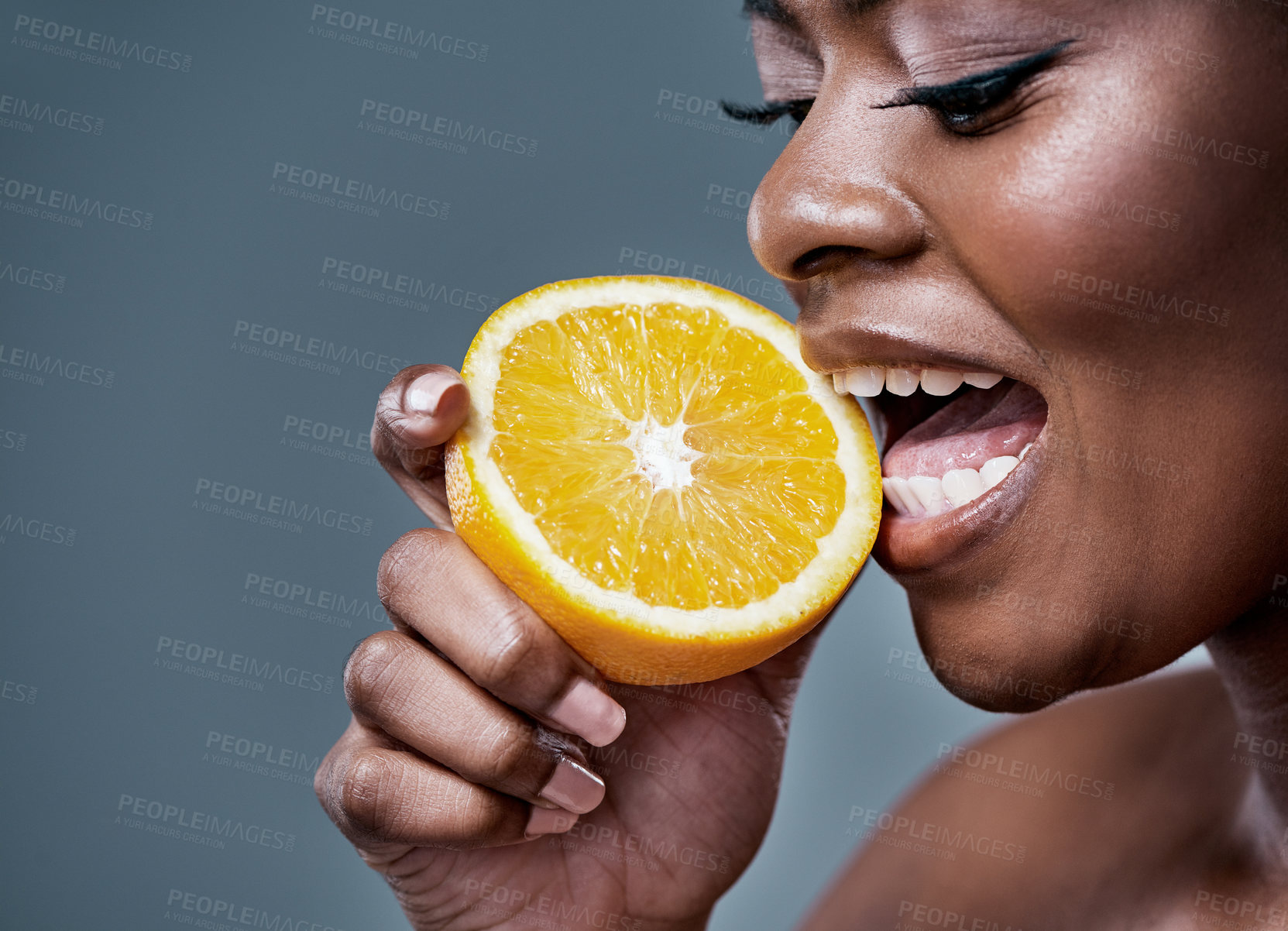 Buy stock photo Cropped shot of a beautiful young woman biting into an orange